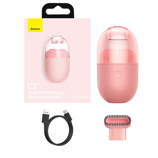 Small rechargeable desktop vacuum cleaner removing dust and debris from office desk setup